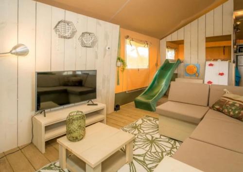 een woonkamer met een bank en een groene glijbaan bij Camping de Brem in Renesse
