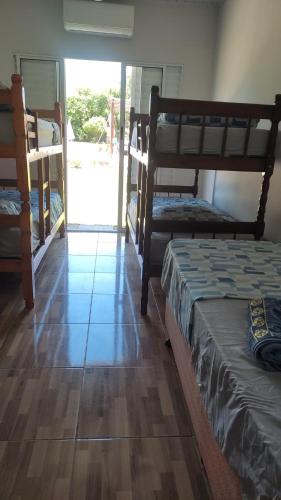a room with three bunk beds and a wooden floor at Complete Chácara Pool, WiFi 5min Thermas in São Pedro