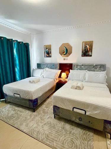 two beds in a room with blue curtains at The Initial Residence in Mombasa