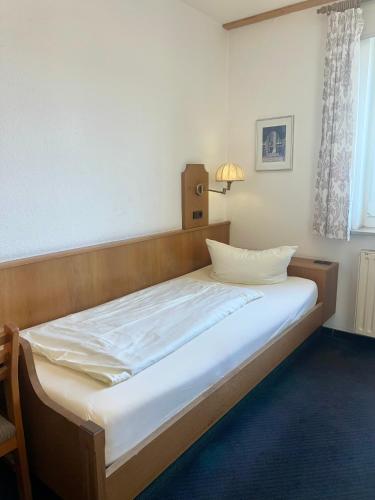 a bed in a room with a white bedsheet at Hotel Feuerbacher Hof in Stuttgart