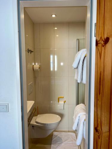 a bathroom with a toilet and a shower with towels at Hotel Feuerbacher Hof in Stuttgart