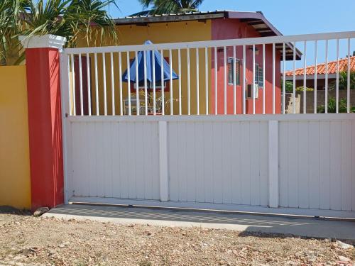 a white fence with an umbrella on it next to a house at Sunny Isle Apartment in Rooi Master