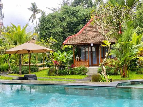 a resort with a swimming pool and a house at Puri Kurnia Ayu in Ubud