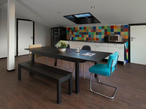 een eettafel met een blauwe stoel en een keuken bij Ghoyhuys in Leiderdorp
