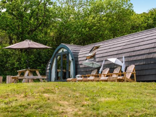 a group of chairs and an umbrella next to a building at Lakeview Lodge- Uk40692 in Crowhurst