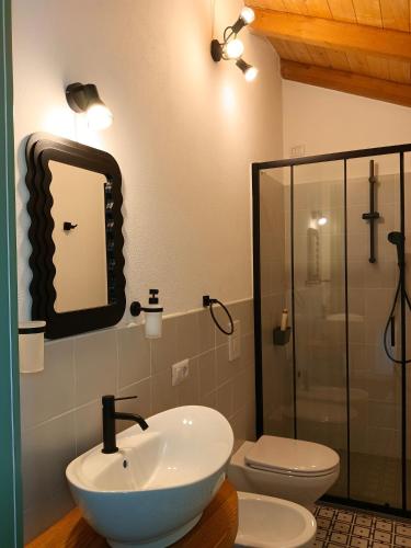 a bathroom with a sink and a toilet and a mirror at La Casa Vecchia in Nuraminis