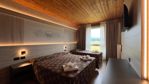a hotel room with two beds and a window at Hotel Vezzena in Malga Postesina