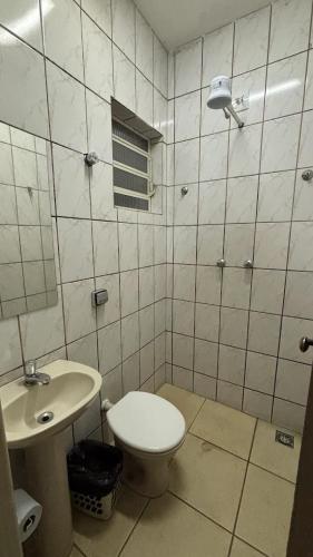 a bathroom with a toilet and a sink at Hotel Olympia in Cláudio