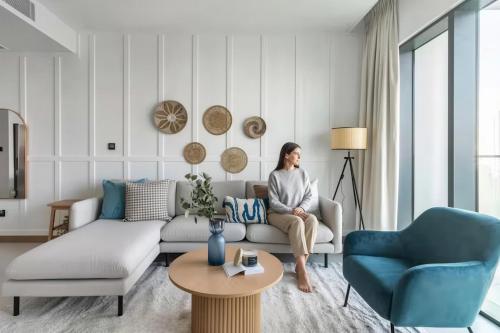 a woman sitting on a couch in a living room at GuestReady - Opulent Residence in Dubai Marina in Dubai