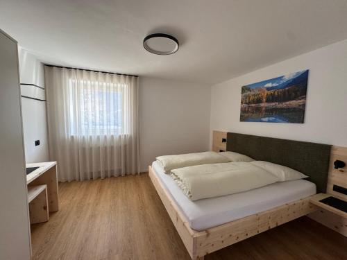 a bedroom with a bed and a desk and a window at Klostergut in Kastelbell-Tschars