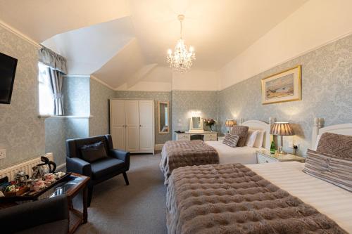 a hotel room with two beds and a chair at Bryn Derwen with Private Car Park in Llandudno