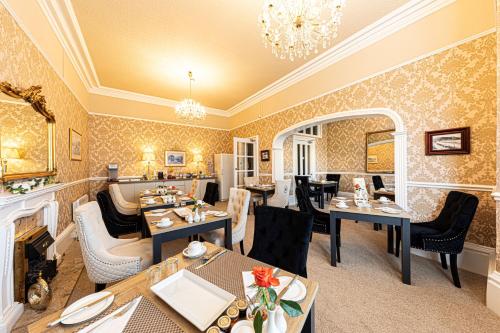 a restaurant with tables and chairs and a fireplace at Bryn Derwen with Private Car Park in Llandudno