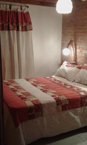 a bedroom with a bed with a red and white blanket at Complejo Rancho Grande in Nueva Atlantis