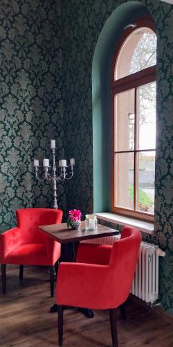 a dining room with red chairs and a table and a window at BBZ Burg Weißensee in Weißensee