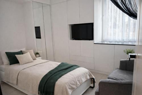 a bedroom with a bed and a tv and a chair at Zielone Stablowice Wrocław in Wrocław