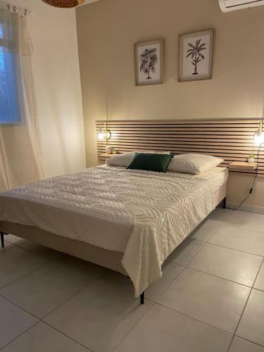 a bedroom with a large bed with two lights on it at Villa de charme à Matoury in Matoury