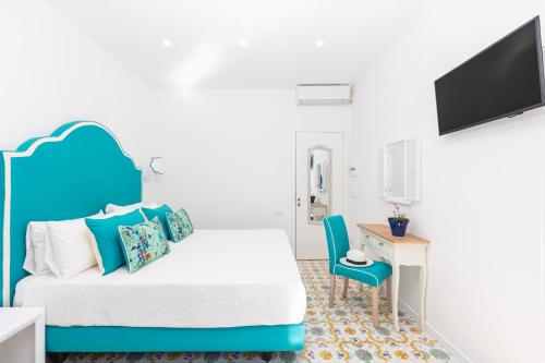 a bedroom with a bed and a desk and a tv at YourHome - Villa Allegria in Positano