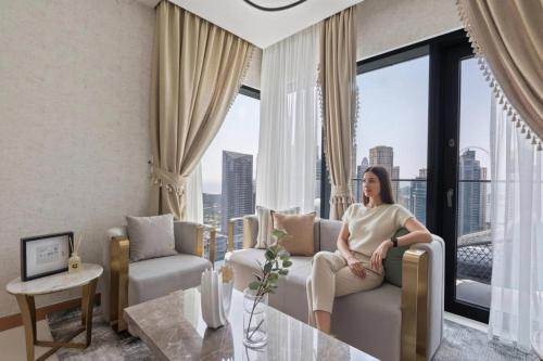 a woman sitting on a couch in a living room at GuestReady - High-floor luxury with Marina view in Dubai