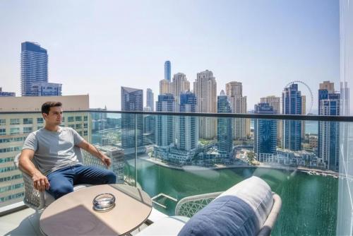 a man sitting at a table on top of a building at GuestReady - High-floor luxury with Marina view in Dubai