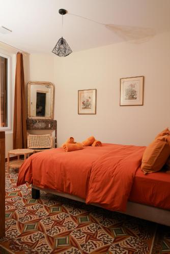 Maison Pamplemousse في آرل: غرفة نوم بها سرير ذو ملاءات حمراء ومرآة