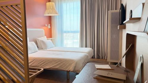 a hotel room with two beds and a window at OKKO Hotels Paris La Défense in Nanterre
