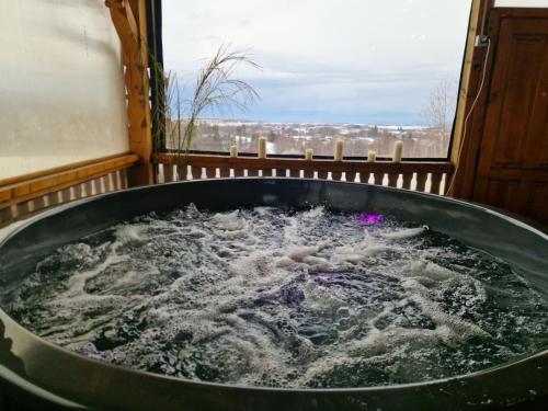 a large tub filled with water next to a window at Cabana Apus de Soare in Râșca