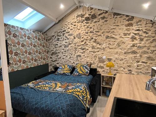 a bedroom with a bed and a stone wall at La Dilettante - petit déjeuner inclus - 10mn du Parc in Treize-Vents