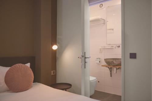 a bedroom with a bed and a bathroom with a toilet at Quentin Canal House Hotel in Amsterdam