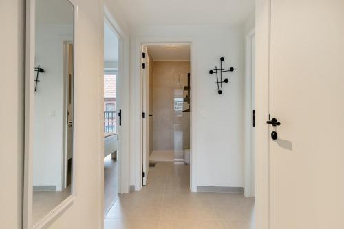 ein Flur mit weißen Wänden und ein weißes Badezimmer in der Unterkunft Flat Scarpato in Kortemark