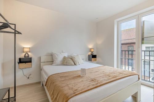 ein weißes Schlafzimmer mit einem Bett und einem großen Fenster in der Unterkunft Flat Scarpato in Kortemark
