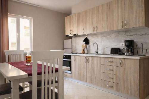 a kitchen with wooden cabinets and a table and a dining room at Dahlila's Home near Lake Ohrid in Pogradec