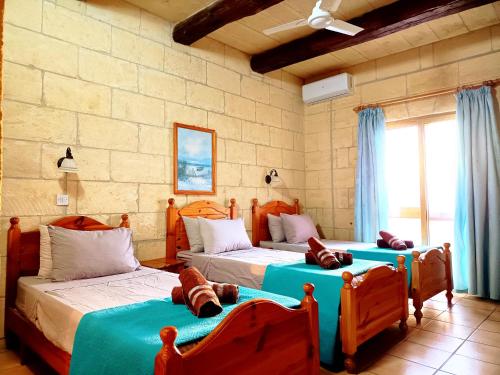 a bedroom with two beds with blue sheets at Ortensia in Taʼ Bullara