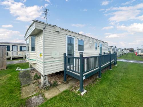 a white mobile home with a blue fence at Emily's Van in Skegness