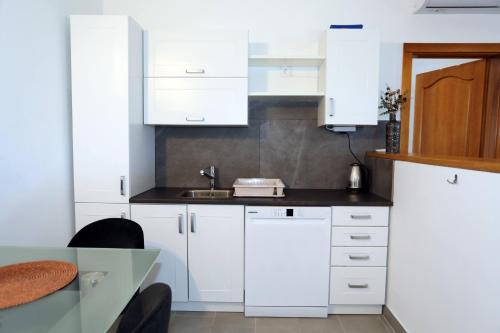 a kitchen with white cabinets and a table at Apolo Apartments - Pool & Garden Retreat in Pula