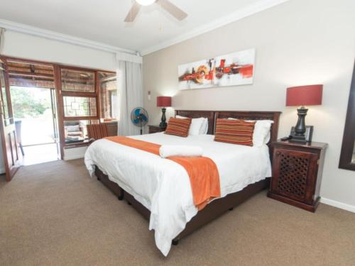 a bedroom with a large bed with an orange blanket at Amani Guest Lodge in Port Elizabeth