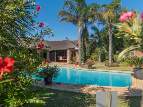 a house with a swimming pool and palm trees at Amani Guest Lodge in Port Elizabeth