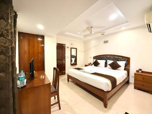 a bedroom with a bed and a desk and a television at Laavish 7 Hotel in Bangalore