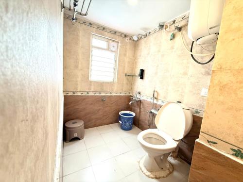 a bathroom with a toilet and a window at Laavish 7 Hotel in Bangalore