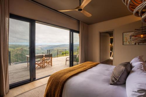 a bedroom with a bed and a view of a deck at Mantis Hiddn in Addo in Addo