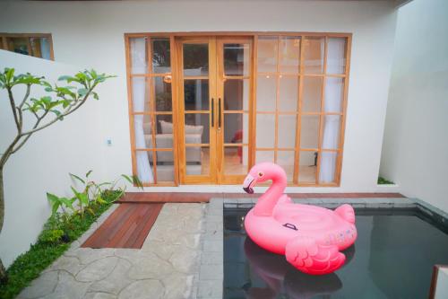 a pink inflatable flamingo in a pool in front of a house at Among Villa Demangan in Yogyakarta