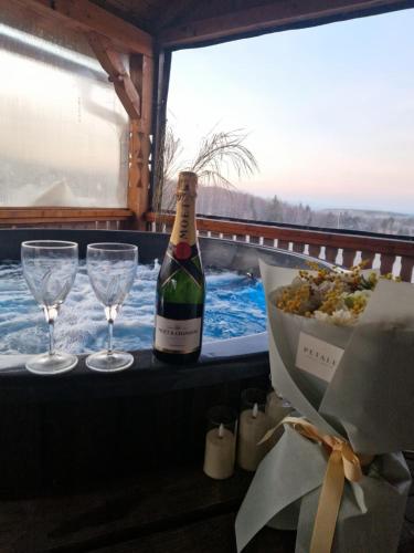 a bottle of wine and two glasses on a table at Cabana Apus de Soare in Râșca