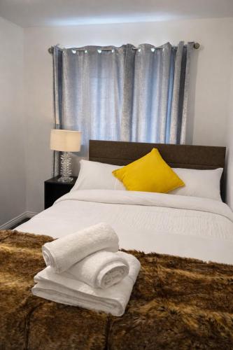 a bed with a yellow pillow and towels on it at New Haven Atherton Greater Manchester in Atherton