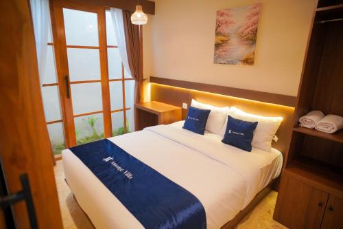a bedroom with a large bed with blue pillows at Among Villa Demangan in Yogyakarta