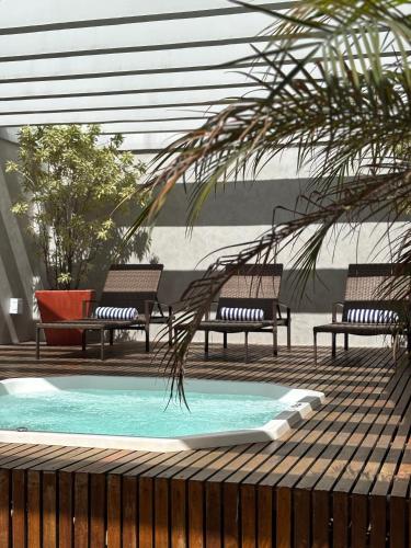 a swimming pool with benches and a palm tree at Promenade Soho Campos dos Goytacazes in Campos dos Goytacazes