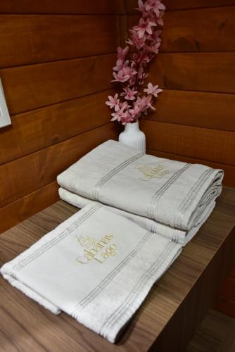 three towels sitting on a table with a vase of flowers at Cabanas Lago - Piratuba-SC in Piratuba