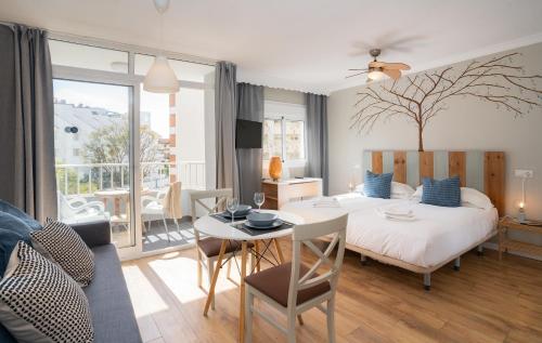 a bedroom with a bed and a table and a dining room at Palm Beach Club Apartamentos Carihuela in Torremolinos