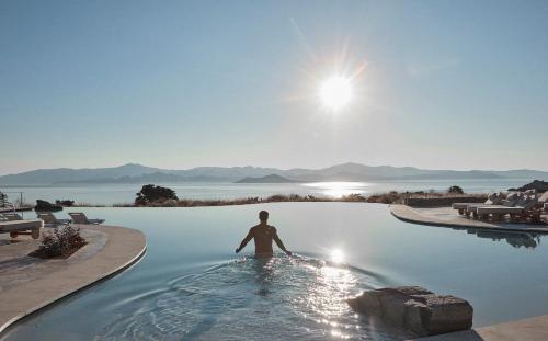a man standing in a swimming pool in the water at Vione Paros in Ambelas