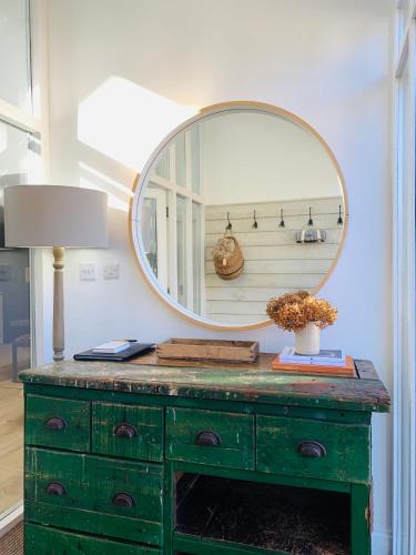 a green dresser with a mirror on top of it at Peartree Cottage in Sandhoe