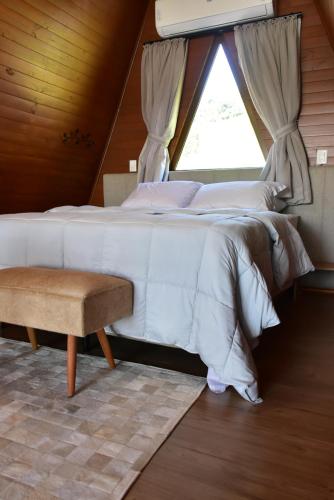 a bedroom with a large white bed with a window at Cabanas Lago - Piratuba-SC in Piratuba