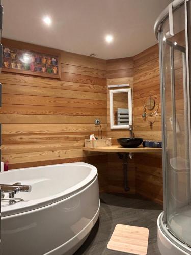 a bathroom with wooden walls and a tub and a sink at Casa 17 Confolens in Confolens